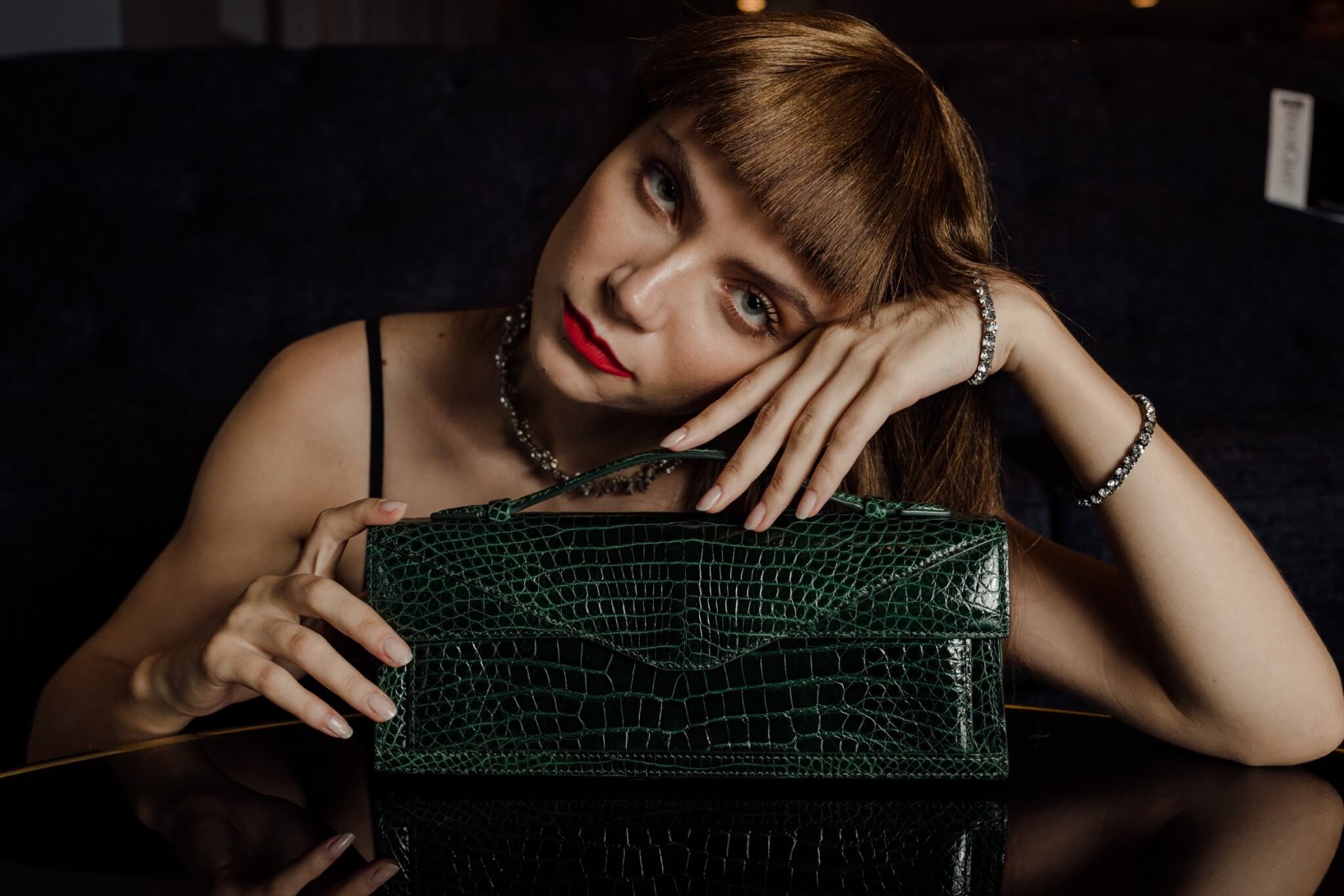 Women holding green crocodile luxury bag from bangkok bootery emerging designers